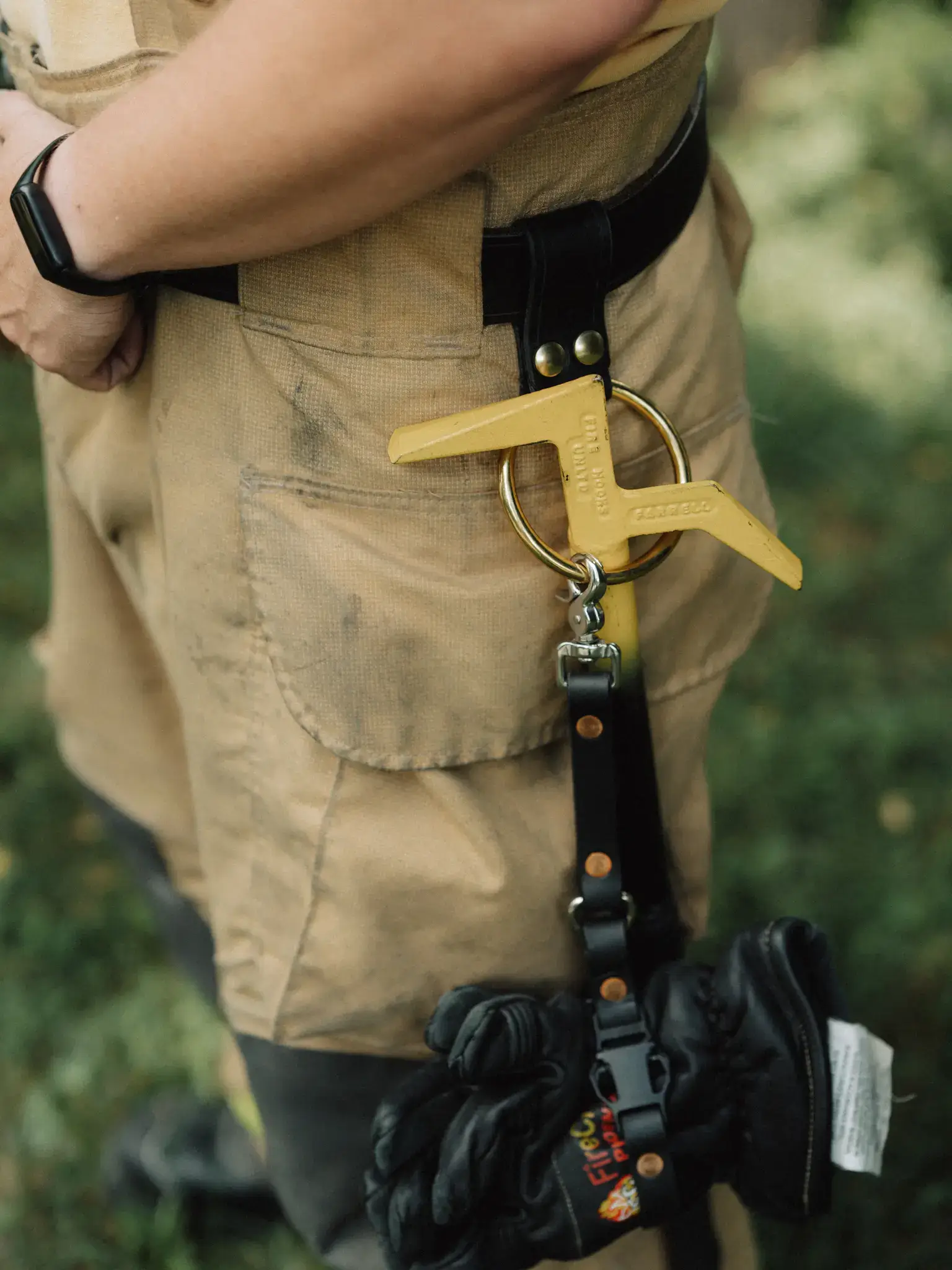 a leather utility tool loop or tool ring is attached to a firefighter's leather turnout belt with a haligan through it