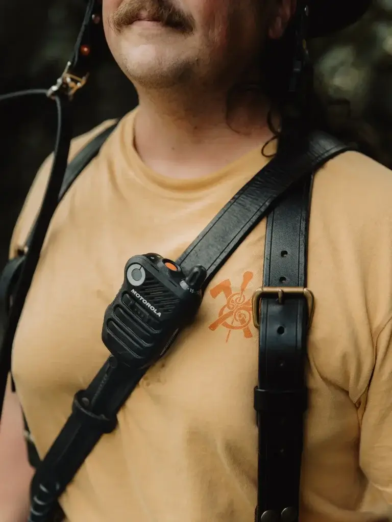 a firefighter wears a black leather radio strap in his turnout gear with an axe and awl leatherworks shop shirt in mustard