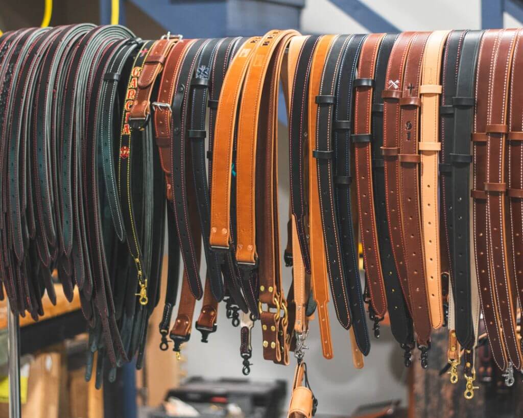 Variety of leather firefighter radio straps hanging on a rack
