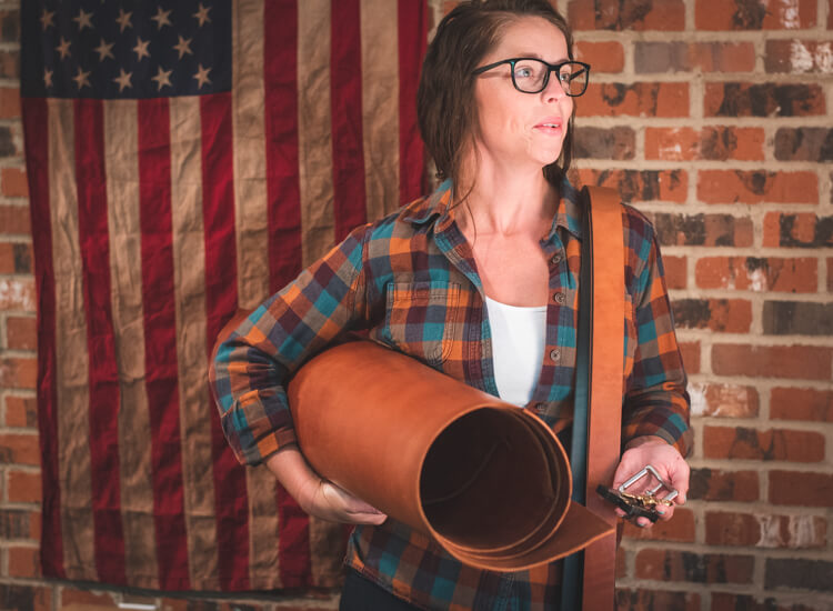 co-founder of axe and awl leatherworks, courtney, holds leather and hardware used to craft leathergoods