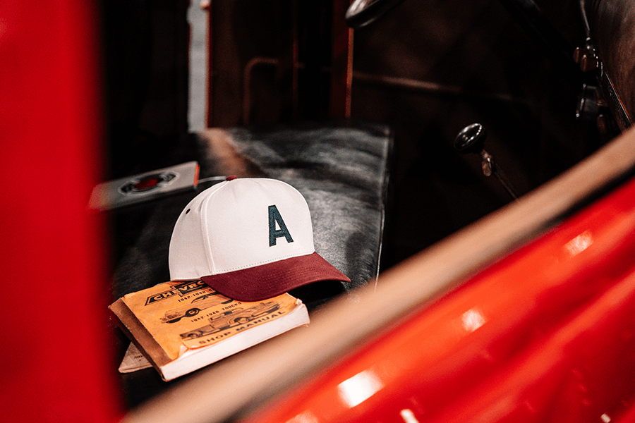 The Axe and Awl Leatherworks Throwback Snapback hat in maroon sitting in a firetruck
