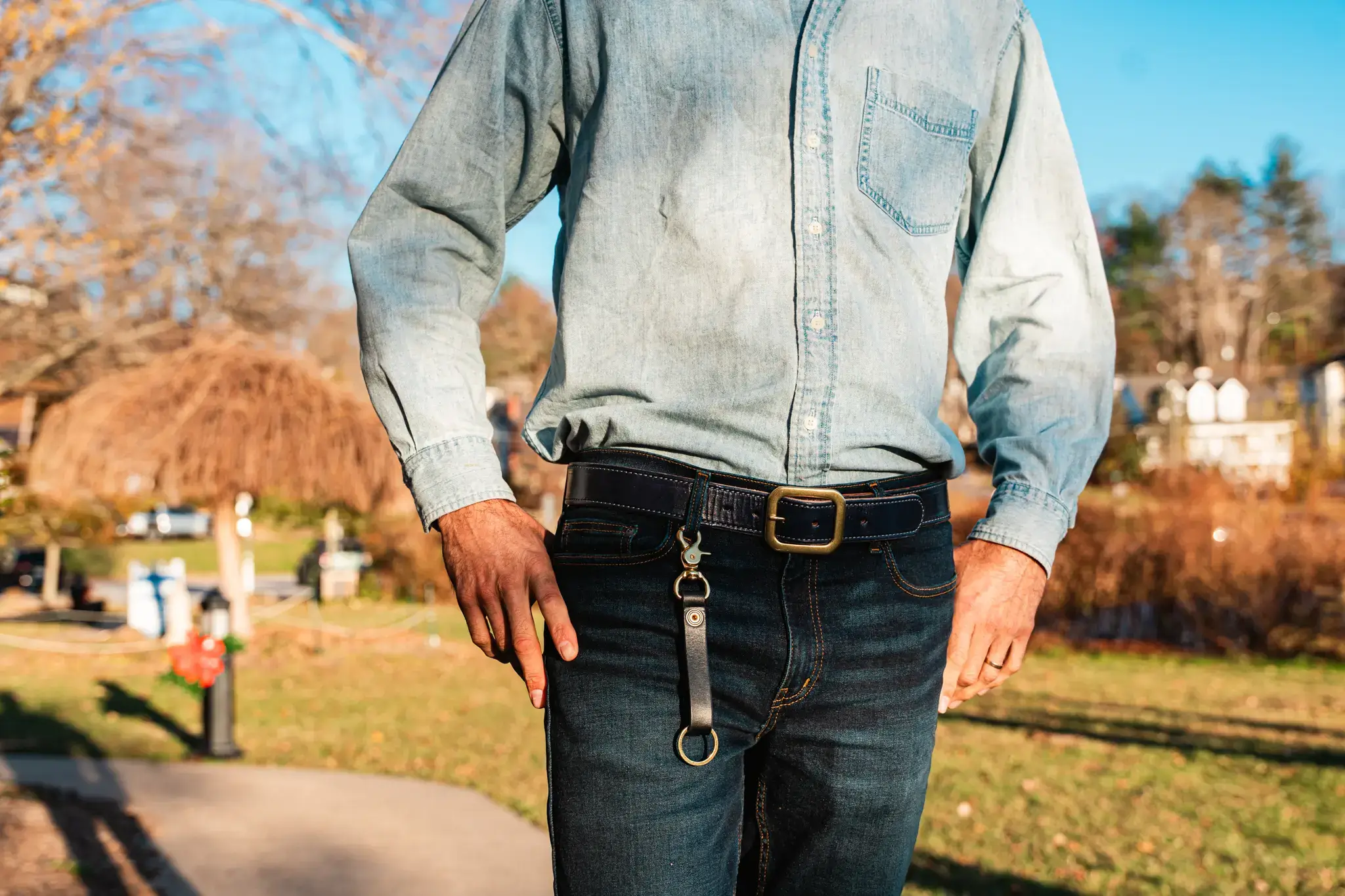 premium harness lined leather wickett and craig belt in navy being worn by a man at lake junaluska, north carolina with a leather key clip from axe and awl leatherworks hanging off of it