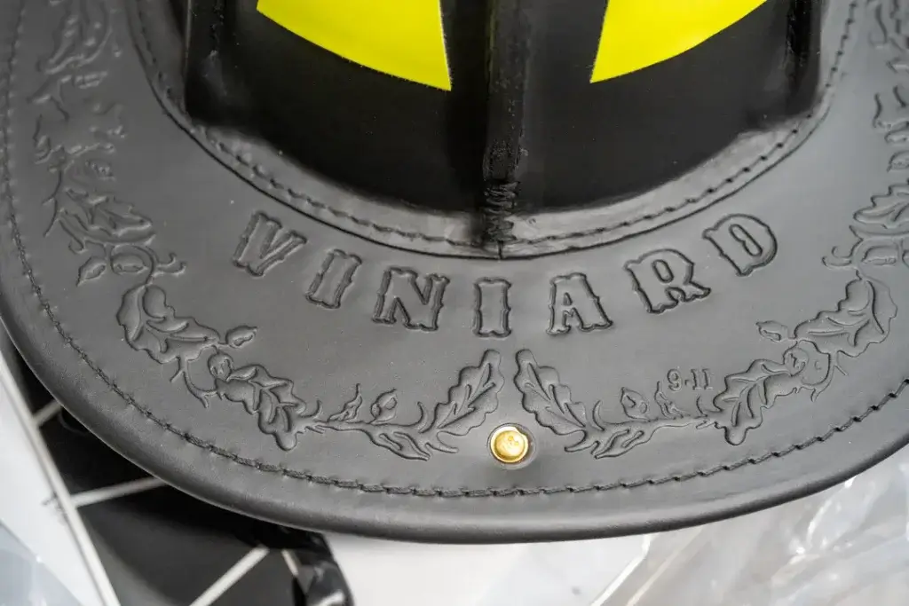 a custom phenix helmet ordered from axe and awl leatherworks is stamped with a fire fighter's last name