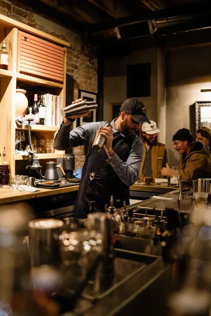 spencer tetrault shakes a cocktail behind the bar at bevel bar inside axe and awl leatherworks