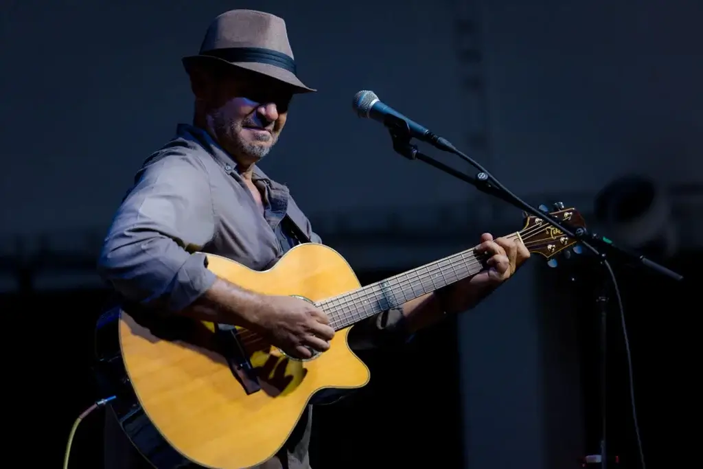 An image of Shane Meade playing guitar with a microphone. 