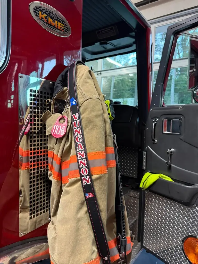 leather fire service radio strap hanging from a fire truck